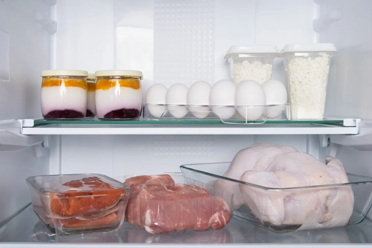 Potraviny uložené na spodnej polici chladničky.